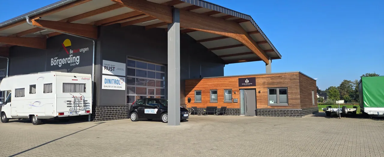 Modern storefront with wooden cladding featuring Dinitrol and Pfote im Glück branding